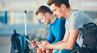 men checking their mobile phones in an airport